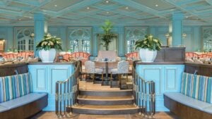 Interior shot of a brightly lit blue dining room with pink accents and plants